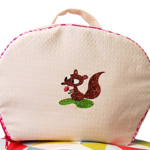 May include: A pink and white oval-shaped zippered bag with a brown squirrel holding a pink flower embroidered on the front.
