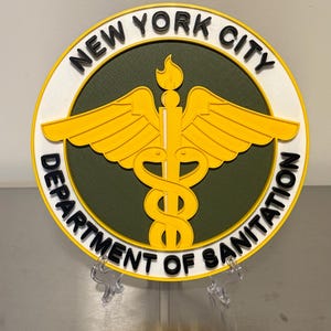 May include: A circular emblem for the New York City Department of Sanitation. The design features a yellow caduceus symbol with wings, a flame, and the text "NEW YORK CITY" and "DEPARTMENT OF SANITATION" in black lettering on a white and green background.