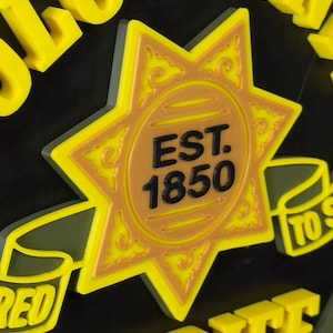 Peut inclure: Panneau jaune et noir avec les mots "LO COUNTY SHERIFF" en lettres en relief. Le panneau pr&eacute;sente une &eacute;toile dor&eacute;e avec le texte "EST. 1850" au centre. Le panneau a une bordure verte.