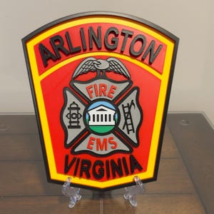 May include: A red, yellow, and black 3D printed patch with the words "Arlington Fire EMS Virginia" and a stylized eagle and fire department symbol.