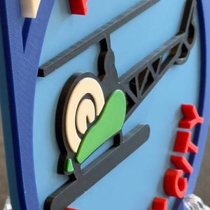 May include: A blue and white 3D printed sign with a red helicopter and the words "Aviation New York City".