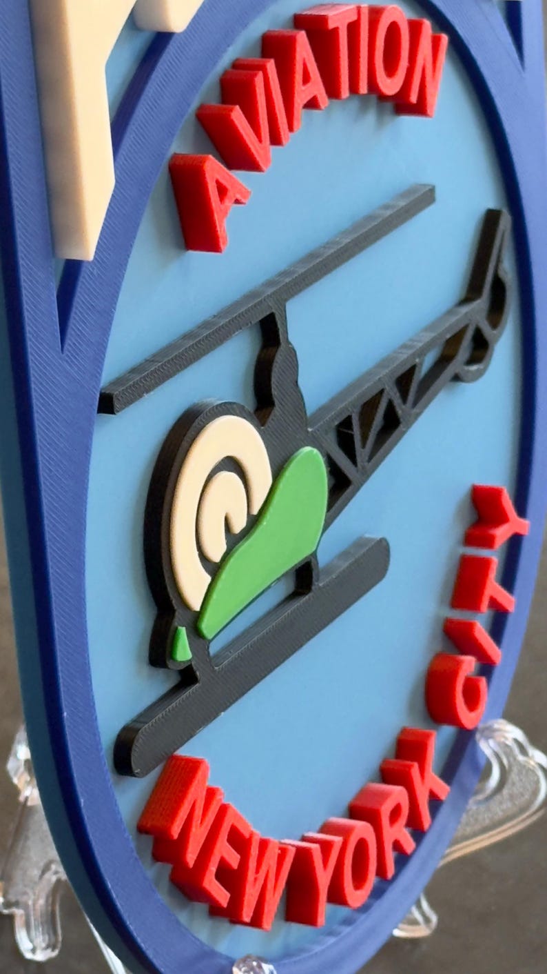 May include: A blue and white 3D printed sign with a red helicopter and the words "Aviation New York City".
