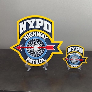 May include: Two layered signs featuring the NYPD Highway Patrol emblem in yellow, dark blue, light blue, white, and red. The design includes the text NYPD HIGHWAY PATROL, a central wheel graphic, and a horizontal red arrow pointing to the left.