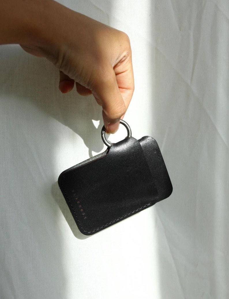 May include: Black leather key chain with a metal ring and the text "luxe goods" embossed on the front.
