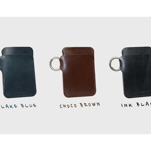 May include: Three leather keychains with metal rings. The keychains are in lake blue, choco brown, and ink black. The keychains are labeled with their colors.