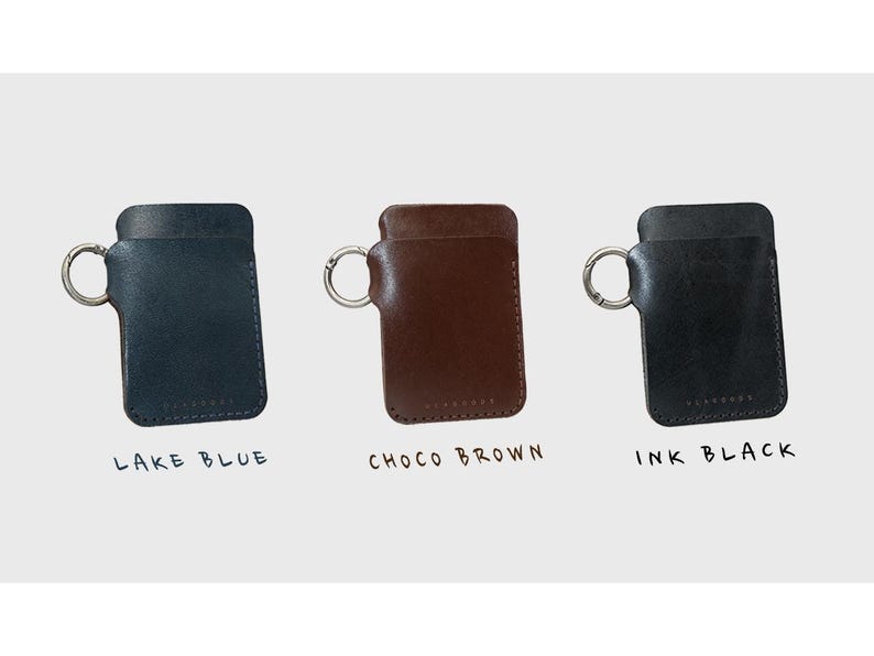May include: Three leather keychains with metal rings. The keychains are in lake blue, choco brown, and ink black. The keychains are labeled with their colors.