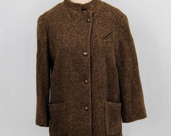 May include: A brown tweed jacket with a stand-up collar, three buttons, and two front pockets. The jacket has a small pocket on the left chest and three-quarter length sleeves. The fabric has a textured appearance.