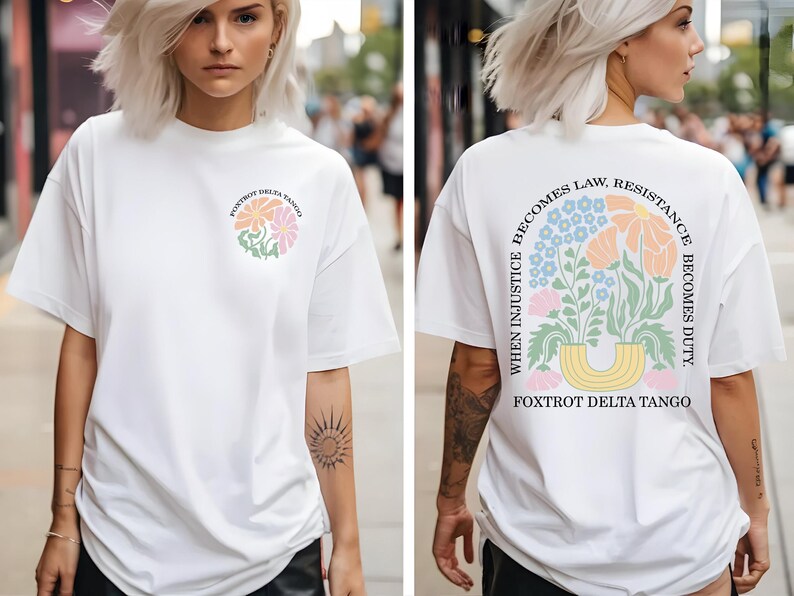 May include: White t-shirt with a floral design and the text "Foxtrot Delta Tango" on the front. The back of the shirt features a floral arrangement and the quote "When injustice becomes law, resistance becomes duty."