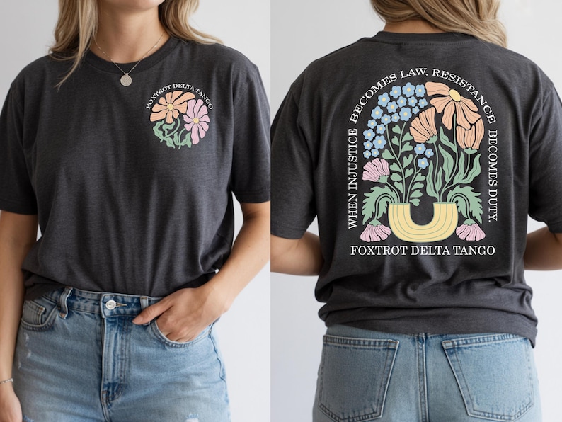 May include: Dark gray t-shirt with a floral design on the front and back. The front features a cluster of pastel flowers and the text "FOXTROT DELTA TANGO." The back displays a floral arrangement with the text "WHEN INJUSTICE BECOMES LAW, RESISTANCE BECOMES DUTY."