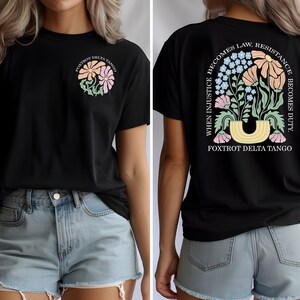 May include: Black t-shirt with a floral design and the text "FOXTROT DELTA TANGO." The back of the shirt features a larger floral arrangement and the quote, "WHEN INJUSTICE BECOMES LAW, RESISTANCE BECOMES DUTY."