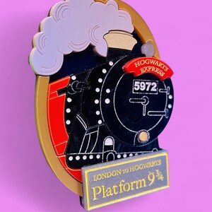 May include: A black and red train engine with gold accents and a white cloud of steam. The train is labeled "Hogwarts Express" and "5972". A sign below the train reads "London to Hogwarts Platform 9 3/4".