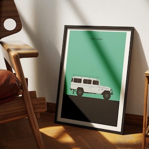 May include: A black framed poster with a green background and a white silhouette of a Toyota Land Cruiser. The poster has the text "TOYOTA LAND CRUISER" at the top.