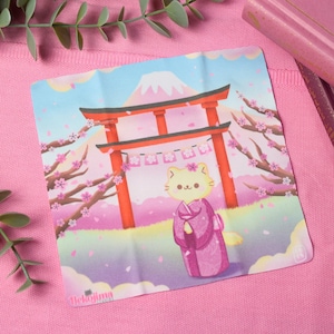 Könnte beinhalten: Eine rosa und weiße Illustration einer Katze, die ein rosa Kimono trägt und vor einem roten Torii-Tor mit einem Berg im Hintergrund steht. Rosa Kirschblüten fallen von den Bäumen.