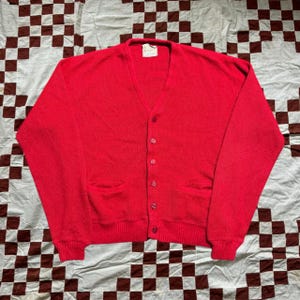 May include: A red cardigan sweater with a V-neck and five button closures. The sweater has two pockets on the front.