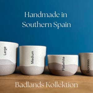 May include: A set of three ceramic mugs with a speckled, matte finish. The mugs are in shades of cream, light gray, and dark gray. Each mug has a simple, minimalist design, perfect for coffee or tea.