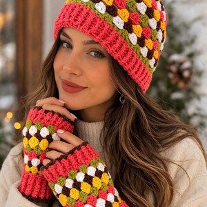 May include: A crochet beanie and matching fingerless gloves set featuring a vibrant granny square pattern in shades of red, yellow, green, white, and brown. The accessories are finished with a solid red ribbed cuff and trim detail.