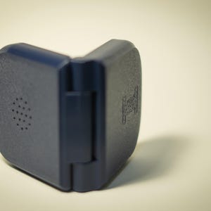 Puede incluir: Una funda de pl&aacute;stico azul oscuro, con bisagras y superficie texturizada. Un lado tiene una serie de peque&ntilde;os agujeros circulares. El otro lado tiene un dise&ntilde;o en relieve. La funda est&aacute; abierta, revelando la bisagra.