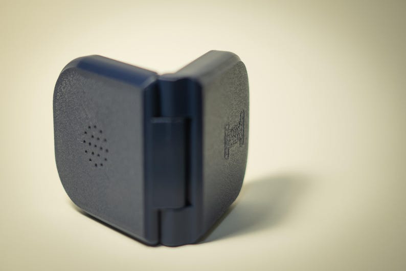 Puede incluir: Una funda de pl&aacute;stico azul oscuro, con bisagras y superficie texturizada. Un lado tiene una serie de peque&ntilde;os agujeros circulares. El otro lado tiene un dise&ntilde;o en relieve. La funda est&aacute; abierta, revelando la bisagra.
