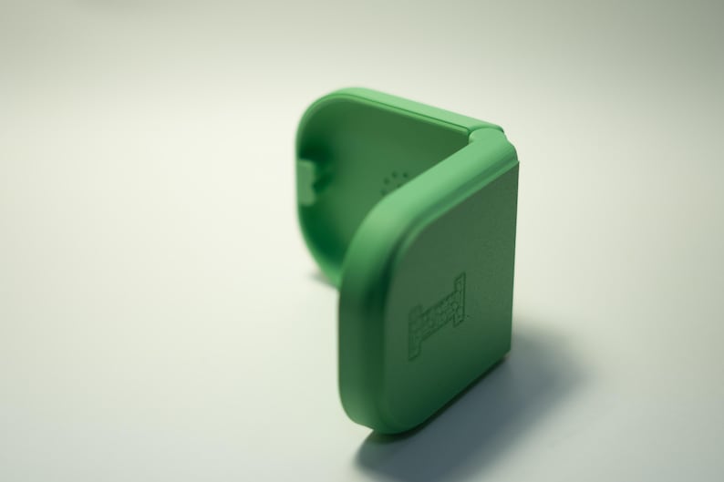 Puede incluir: Un estuche verde claro, abierto, de forma cuadrada con esquinas redondeadas. El estuche est&aacute; hecho de un material s&oacute;lido y tiene un peque&ntilde;o dise&ntilde;o en relieve en la parte delantera. El estuche est&aacute; abierto, revelando el interior.