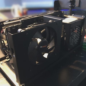 Könnte beinhalten: Ein schwarzes Computergehäuse mit sichtbaren internen Komponenten. Ein großer Lüfter mit dem Text "be quiet!" ist prominent. Weitere Komponenten sind ein kleinerer Lüfter und verschiedene Leiterplatten. Das Gehäuse ist geöffnet.