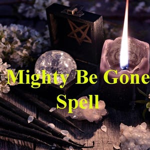 May include: A mystical arrangement with a lit candle, a crystal ball, and a box with a star. The text reads "Mighty Be Gone Spell". White flowers and crystals are arranged around the objects on a wooden surface.