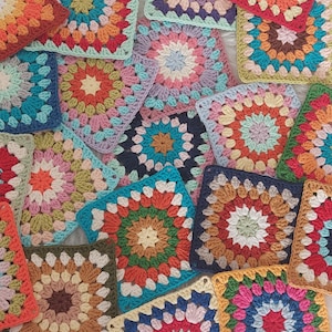 Peut inclure: Une collection de carrés de grand-mère au crochet colorés avec une variété de couleurs et de motifs. Les carrés sont faits avec des fils de différentes couleurs et présentent un cercle central avec des pétales rayonnants.