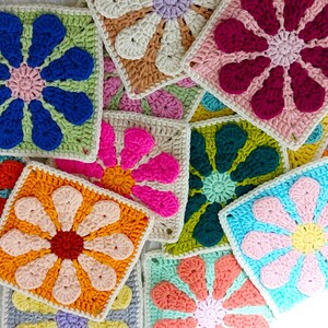 May include: A collection of colorful crocheted flower squares in various colors, including pink, blue, green, orange, and yellow. The squares are made with a granny stitch pattern and feature a raised flower design in the center.