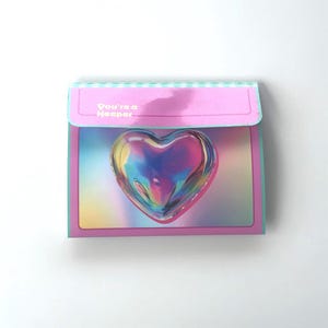 May include: A pink and blue card with a holographic heart and the text "You're a Keeper".