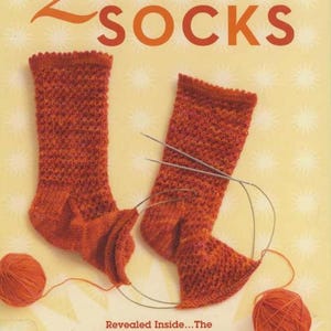 May include: A book cover titled "2-at-a-time SOCKS" by Melissa Morgan-Oakes. The cover features two orange knitted socks with needles, yarn balls, and text that reads "Revealed Inside... The SECRET of Knitting Two at Once on One Circular Needle WORKS FOR ANY SOCK PATTERN!"