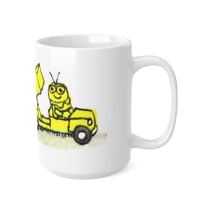 May include: White ceramic mug featuring a yellow cartoon caterpillar driving a yellow car. The caterpillar has a smiling face and is wearing glasses.