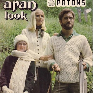 May include: Vintage book cover featuring a family in cream-colored Aran knit sweaters, scarves, and hats. The text reads "the Aran look" and "Patons". The family is standing outdoors in front of a green background.
