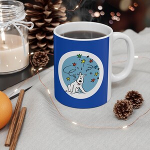 May include: A white ceramic mug with a blue exterior featuring a cartoon dog design. The design includes the dog, stars, and the word "C'est". The mug has a white handle and is filled with a dark liquid.