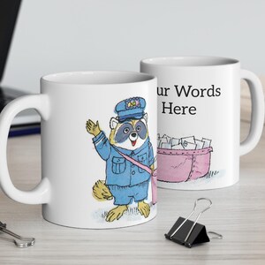 May include: White ceramic mug featuring a cartoon raccoon dressed as a mail carrier, waving with one hand. The raccoon wears a blue uniform and hat. The second mug has the text "Your Words Here" and a pink mail bin.