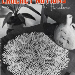 May include: A white ceramic mug with a black handle and the text "But First, Coffee" in a bold, black font. The mug is set against a blurred background, suggesting a cozy setting.