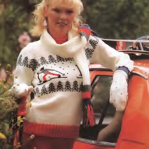 May include: A white knitted sweater with a ski scene design, paired with a matching scarf. The sweater features a red and black ski lift and tree pattern. The outfit is completed with red pants and a red trim on the sweater.