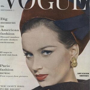 Może przedstawiać: Okładka magazynu Vogue z kobietą o niebieskich oczach i czerwonej szmince, noszącą brązowy kapelusz z niebieską wstążką. Tekst zawiera "Big moment in American fashion" i "Paris fashion news".