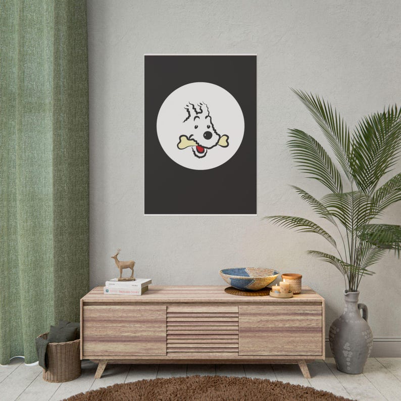 Puede incluir: Un estampado enmarcado que presenta un perro de dibujos animados con un hueso en la boca, sobre un fondo negro dentro de un c&iacute;rculo blanco. La obra de arte se exhibe sobre un mueble de madera con objetos decorativos, incluyendo una peque&ntilde;a figura de ciervo y una cesta tejida.