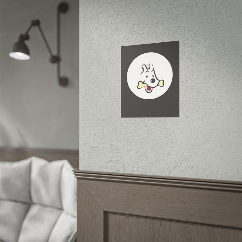 Puede incluir: Una impresi&oacute;n enmarcada con un perro de dibujos animados con un hueso en la boca, sobre un c&iacute;rculo blanco sobre un fondo gris oscuro. El perro est&aacute; representado en negro y rojo. La impresi&oacute;n est&aacute; montada en una pared.