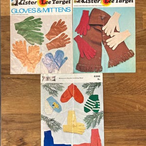 May include: Three vintage Lister Lee Target knitting pattern booklets featuring illustrations of various knitted gloves, mittens, and a scarf. The covers display colorful hand-knit items in green, brown, orange, blue, red, white, yellow, and striped patterns with text including K748, K749, and 6306.