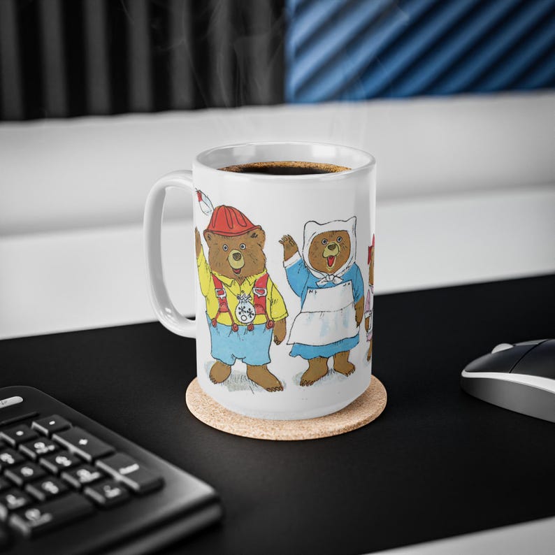 May include: White ceramic coffee mug with a colorful illustration of three bears wearing clothes. The bears are a firefighter, a nurse, and a chef. The mug is sitting on a cork coaster.