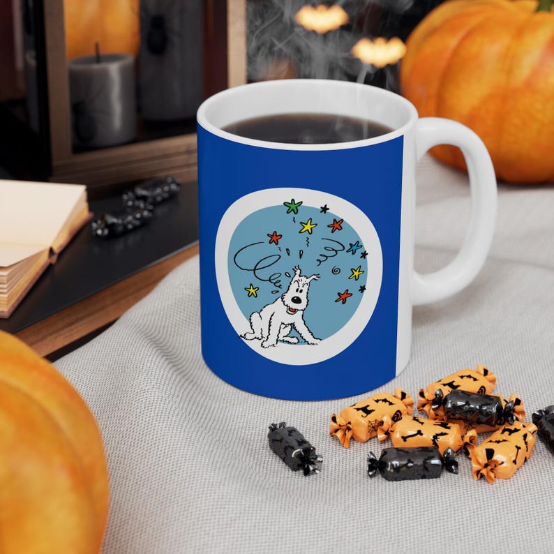 May include: A white ceramic mug with a blue exterior featuring a cartoon dog design. The dog is white with a blue background and colorful stars. The mug has a white handle and is filled with a dark liquid.