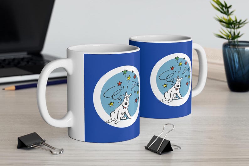 May include: Two white ceramic mugs with a blue design featuring a cartoon dog and colorful stars. The mugs have a white handle and a blue background. The word "Cheers" is written above the dog.