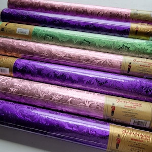 May include: A collection of six rolls of Guardsman Brand Windsor embossed foil wrapping paper in alternating shades of metallic pink, purple, and green. Each roll features a repeating floral damask pattern and a gold label with text.