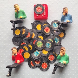 May include: A collection of vintage miniature vinyl records with colorful labels, surrounded by small figurines of people on the phone. A red miniature record player is also present. The figurines are wearing green, red, and blue shirts.
