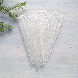 May include: A collection of clear, twisted plastic icicle ornaments, each featuring a small integrated hook at the top for hanging. These transparent, elongated decorations mimic the appearance of natural ice formations with a spiraled texture.