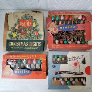 Pode incluir: Quatro caixas vintage de luzes de Natal. As caixas são rotuladas como "Usalite" e "Ever-Lite" e apresentam lâmpadas coloridas. As caixas têm designs retrô com texto que diz "Christmas Lights" e "15 Light Multiple Outfit".