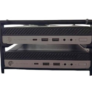 May include: A black plastic storage rack holding two stacked silver and black HP EliteDesk mini desktop computers. Each computer features a front panel with USB ports, audio jacks, and a power button, all organised within the two-tier frame.