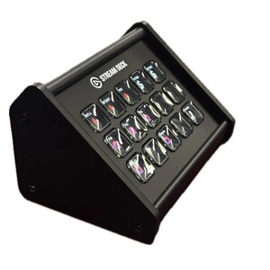 May include: Black Stream Deck with 15 illuminated buttons. The buttons have various icons and text. The Stream Deck is angled upwards and has the Stream Deck logo on the top.