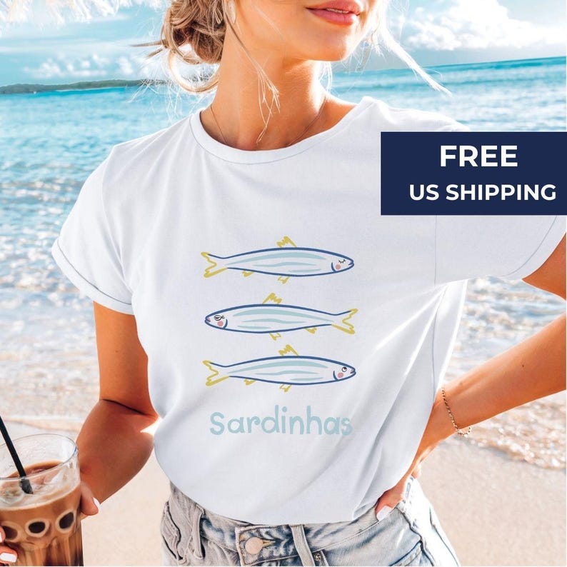 A happy woman wearing the Cute Sardines T-Shirt, styled as a Girls' Weekend Tee for a fun, relaxed beach day. The ocean-inspired design makes it a perfect coastal shirt, ideal for seafood lovers and vacation vibes