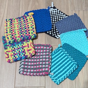 May include: A set of nine colorful crocheted pot holders in various patterns, including checkered, striped, and geometric designs. The pot holders are made with a variety of colors, including blue, green, pink, yellow, and black.